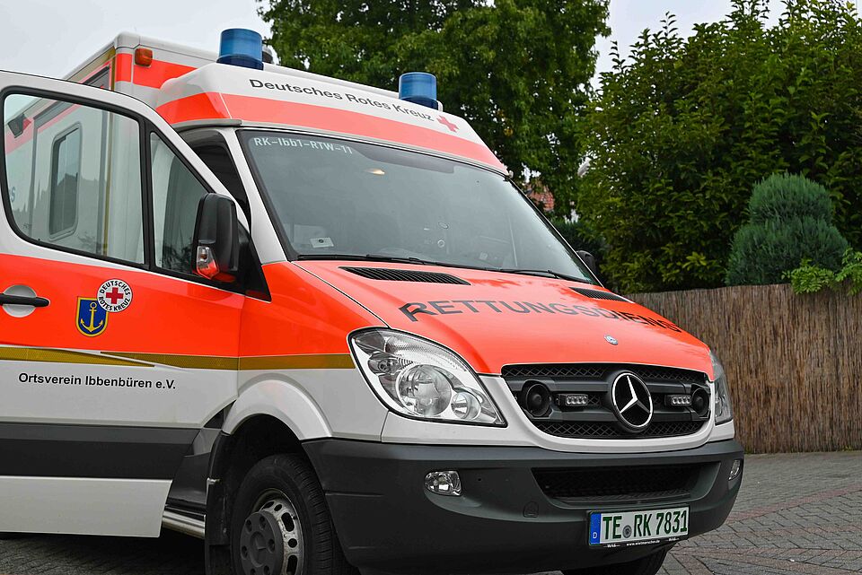 Ein Rettungswagen des Deutschen Roten Kreuzes mit geöffneter Fahrertür steht im Freien. Auf der Fahrzeugseite ist „Ortsverein Ibbenbüren e.V.“ zu lesen.