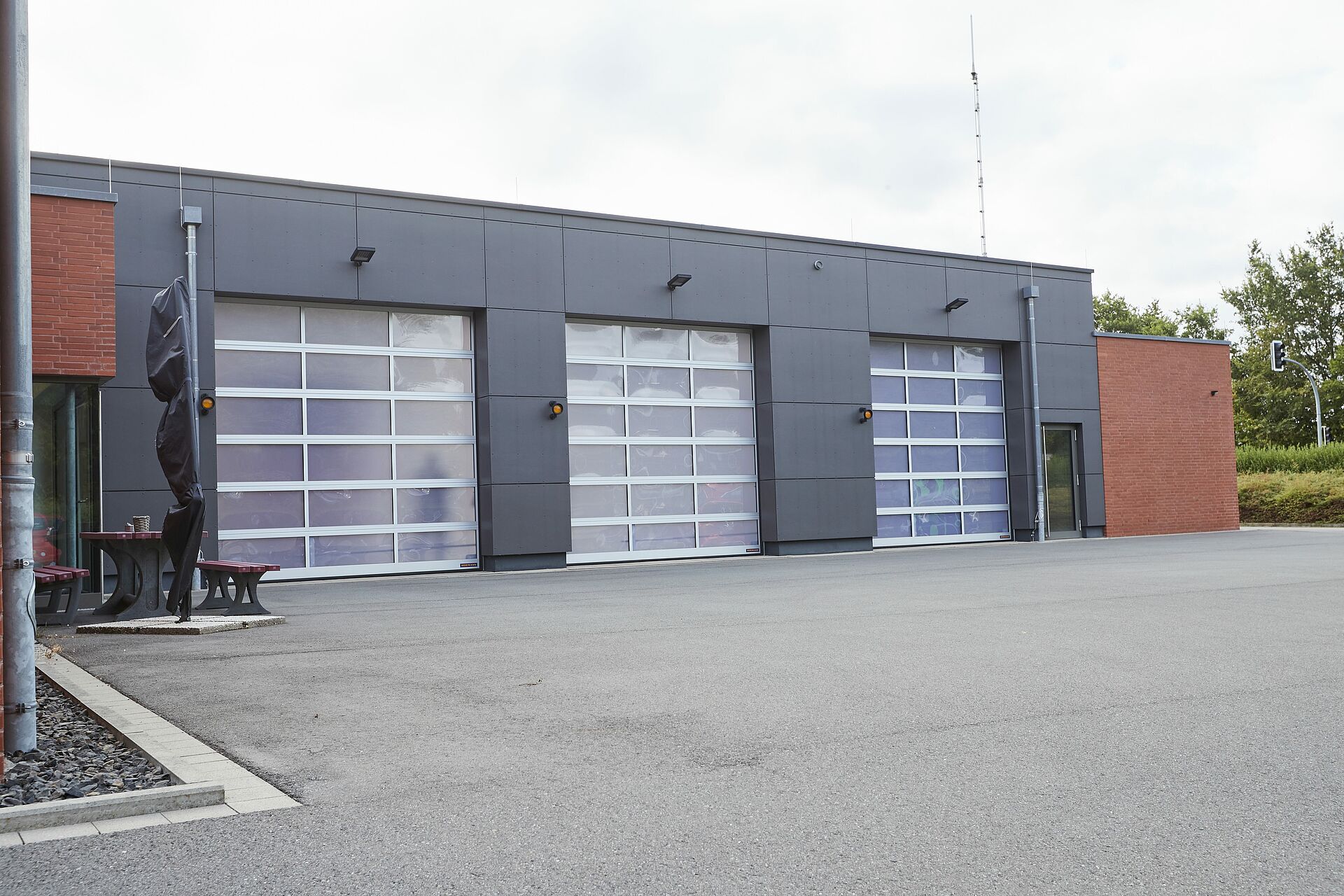 Außenansicht der DRK-Rettungswache in Westerkappeln: Das moderne Gebäude mit dunkler Fassade und roten Backsteinakzenten besitzt drei große geschlossene Garagentore
