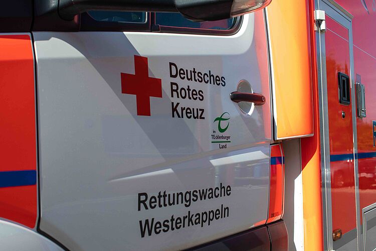 Ein Seitenansicht eines weißen Rettungswagens mit dem Logo des Deutschen Roten Kreuzes und dem Schriftzug "Rettungswache Westerkappeln".